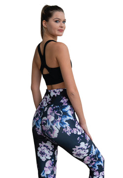 Frau in Lisminas 334 High Waist Leggings in Rosa geblumt und schwarzem Sporttop, blickt vor weißem Hintergrund zurück.