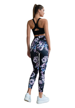 Frau in Lismina 334 High Waist Schwarz, Blau, Rosa geblumt Leggings und weißen Sneakers, Pferdeschwanz nach außen gerichtet.