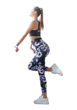 Frau in Lisminas 334 High Waist Schwarz, Blau, Rosa geblümten Leggings und BH-Posen, die Bewegungsfreiheit betonen.