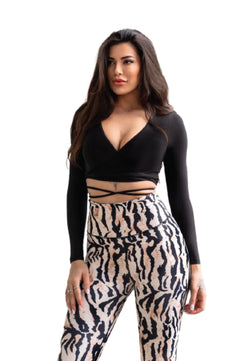 Eine Frau in einem schwarzen Oberteil und Lisminas 303 Extra High Waist Leggings, Beige & Schwarz gemustert, steht vor Weiß.