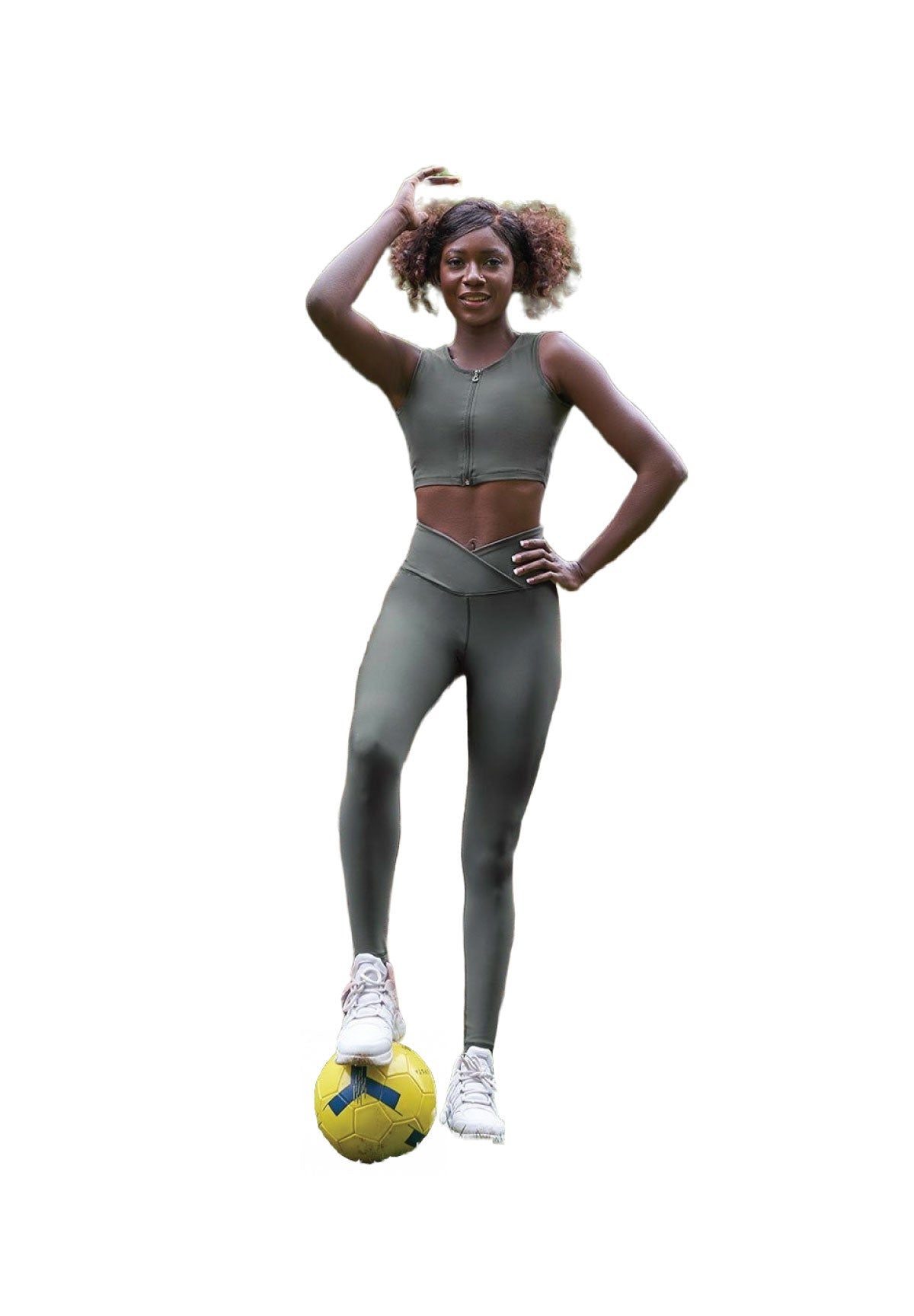 Eine Person in den Lismina 1052 High Waist Khaki Leggings steht mit einem Fuß auf einem gelben Fußball, lächelt und posiert.