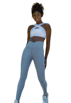Frau in einem weißen Sport-BH und Lismina 1097 Ve Waist Leggings in Wasserblau lächelt vor einem schlichten weißen Hintergrund.